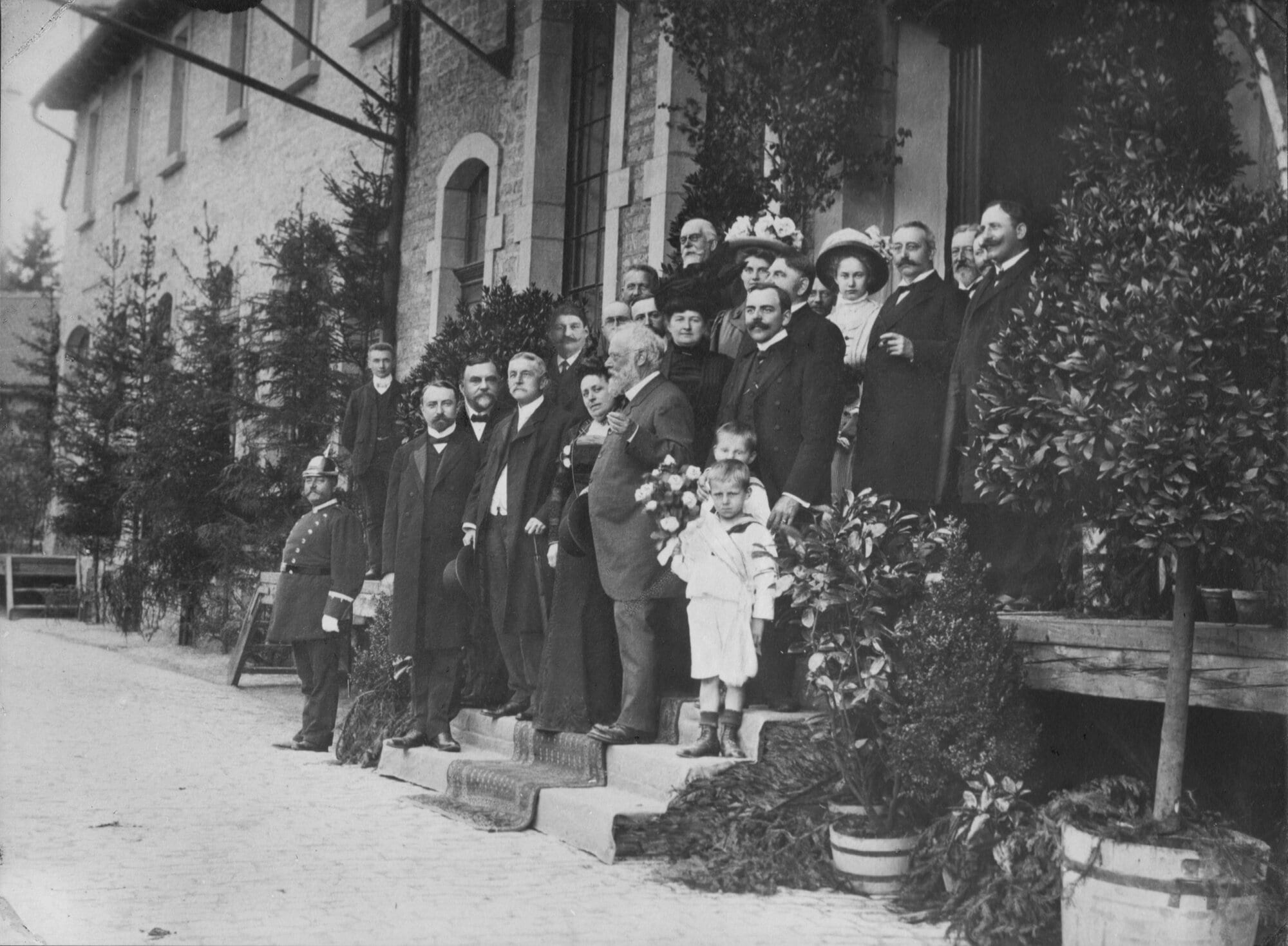 Historische Gruppenaufnahme der Familie Meuschel und Gästen vor dem Eingang des Firmengebäudes